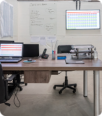 Imagem de um escritório de trabalho com computadores, mesa, cadeira e materiais de escritório, ambiente moderno e organizado.