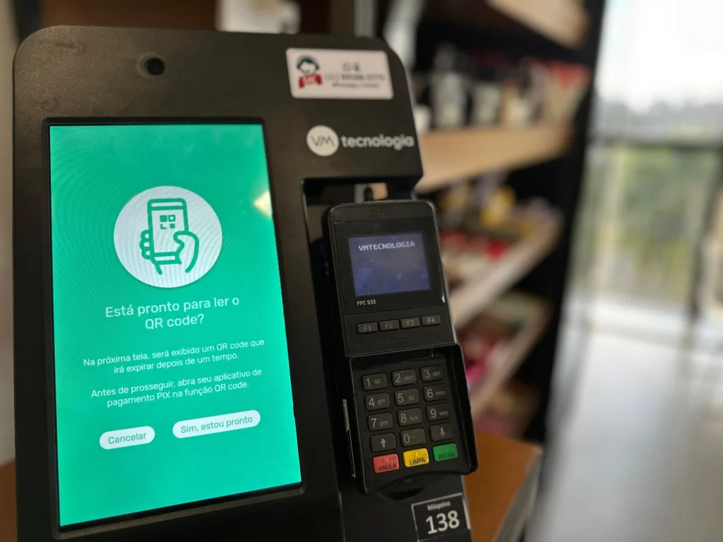 Imagem de uma máquina de cartão de crédito ou débito no interior de um estabelecimento comercial, ambiente com prateleiras ao fundo, destacando a funcionalidade de pagamento por cartão, ideal para negócios que aceitam pagamento com cartão de crédito ou débito.