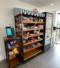 Estação de venda de cigarrilhas e accessories para fumar, com expositores de madeira e sistema de pagamento eletrônico ao lado.